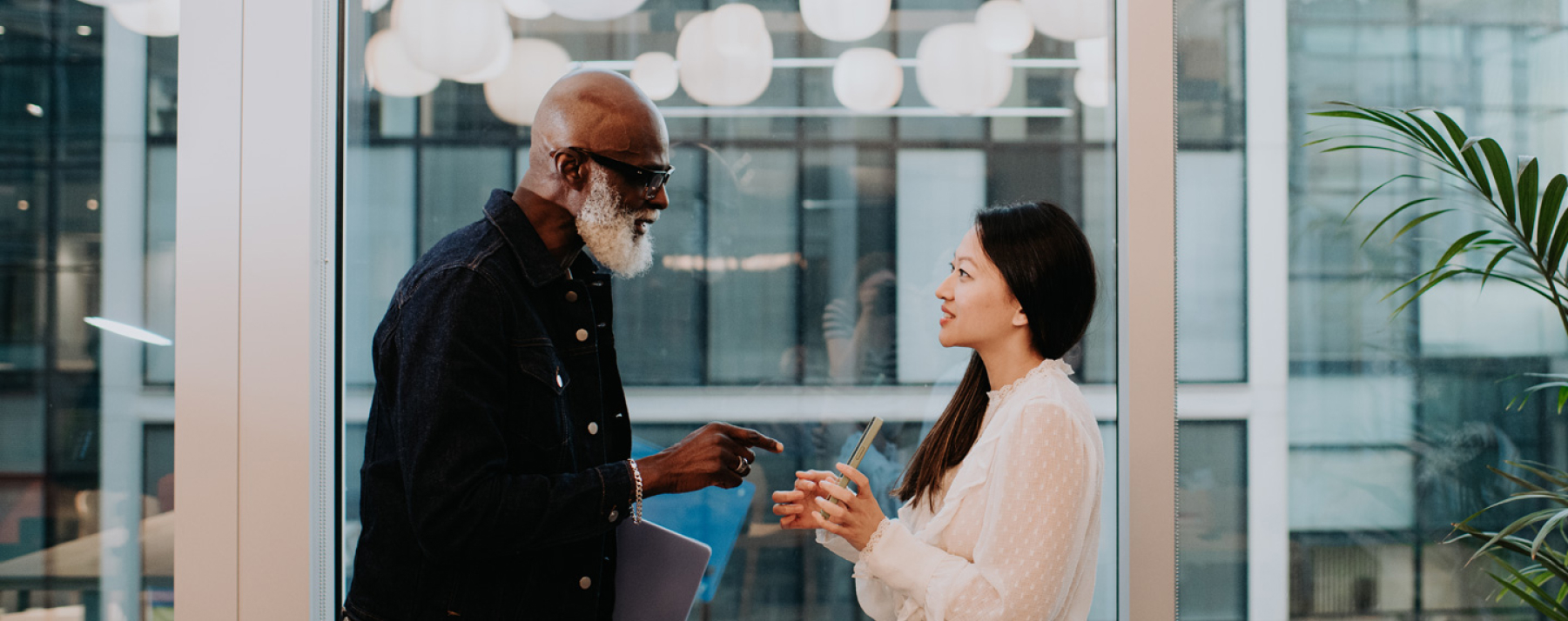 Equipo de trabajo conversando. Hombre afroamericano barba blanca y mujer asiatica