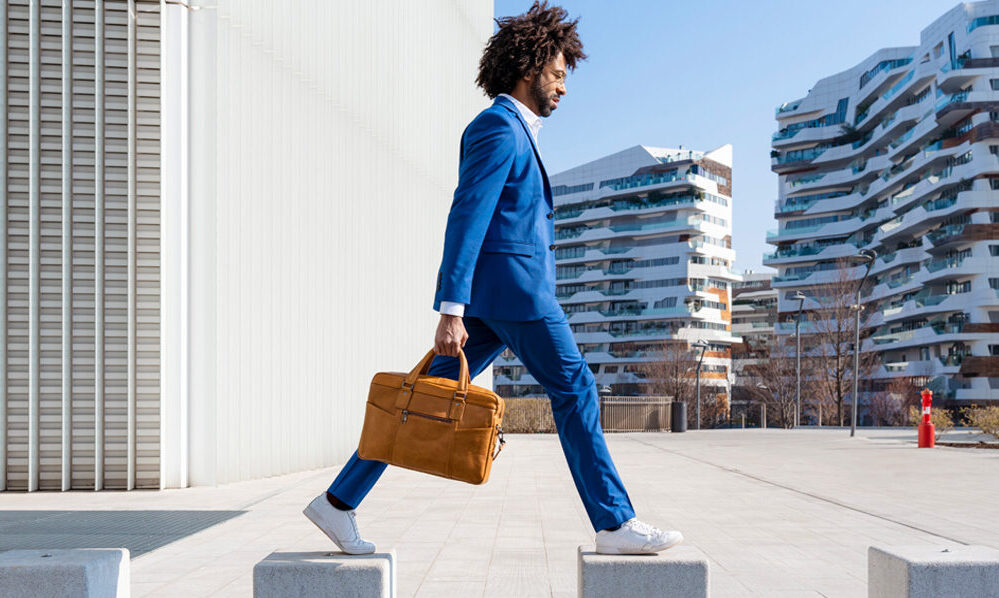 Hombre afroamericano de traje azul y portafolio caminando por la cuidad