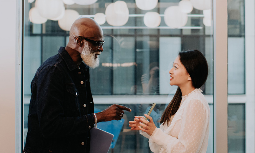 Equipo de trabajo conversando. Hombre afroamericano barba blanca y mujer asiatica